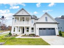 Two-story farmhouse-style home with gray garage doors and a front porch at 2003 Cedar Falls Dr # 69, Waxhaw, NC 28173