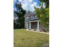 Two-story brick home with a front porch and landscaped lawn at 2044 Sweet William Dr, Harrisburg, NC 28075