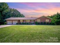 Brick ranch home with a two-car garage and lush lawn at 1418 Oakwood Ave, Kannapolis, NC 28081