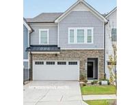 Two-story townhome with gray siding, stone accents, and a two-car garage at 10611 Audubon Ridge Dr # 26, Cornelius, NC 28031