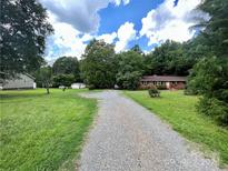 Ranch home with a gravel driveway and large yard at 5419 Stevens Mill Rd, Matthews, NC 28104