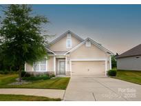 Beige house with two-car garage and landscaped lawn at 124 Rosebay Dr, Mooresville, NC 28117