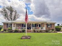 Brick ranch home with covered porch and American flag at 1470 River Hills Ct, Taylorsville, NC 28681