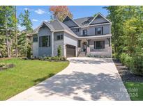Two story house with stone and gray siding, a three car garage, and landscaping at 1106 Anniston Pl # 51, Indian Trail, NC 28079