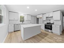 Updated kitchen features white shaker cabinets, quartz countertops, and stainless steel appliances at 115 E Georgia Ave, Bessemer City, NC 28016
