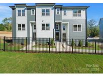 Modern 3-unit townhome building with gray and white siding, black fence, and landscaping at 8009 Elevate Ct, Charlotte, NC 28205
