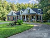 Brick home with white trim, a circular driveway, and landscaping at 10227 Mount Holly Rd, Charlotte, NC 28214