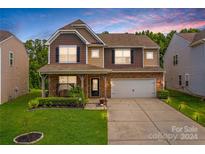 Two-story house with stone and brown siding, a two-car garage, and landscaping at 133 Lassen Ln, Mooresville, NC 28117