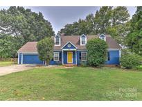 Charming blue house with a yellow door, two-car garage, and well-maintained lawn at 13901 Phillips Rd, Matthews, NC 28105