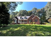 Brick home nestled on a hill with a large yard and mature trees at 926 Courtney Ct, Concord, NC 28025