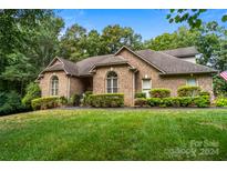 Brick house with a landscaped lawn and mature trees at 10235 Mount Holly Rd, Charlotte, NC 28214