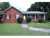 Brick ranch home with a landscaped lawn and a charming front porch at 2209 Laura Dr, Charlotte, NC 28212