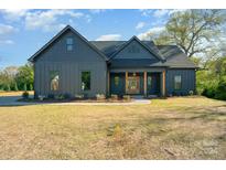 Gray farmhouse exterior with covered porch and landscaping at 1029 Baylor Grv, Monroe, NC 28110