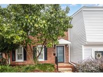 Brick townhome with a landscaped yard and gray front door at 8017 Regent Park Ln, Charlotte, NC 28210