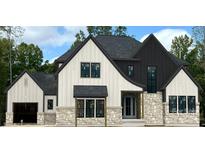 Two-story modern farmhouse with white and black siding, stone accents, and a three-car garage at 136 Castleview Ln, Mooresville, NC 28115