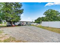 Mobile home with gravel driveway and white vinyl fence at 7686 Hickory Creek Dr, Denver, NC 28037