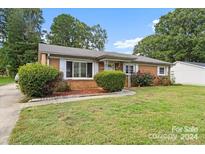 Brick ranch house with landscaped yard and driveway at 6343 Covecreek Dr, Charlotte, NC 28215