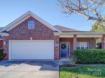 Brick ranch home with attached garage, landscaping, and wreath on door at 104 Aberdeen Dr, Troutman, NC 28166