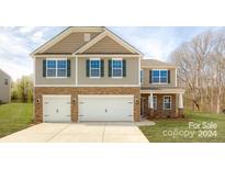 Two-story house with a stone and beige facade, two-car garage, and landscaping at 8054 Kennesaw Dr, Gastonia, NC 28056