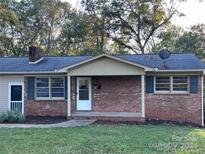 Brick ranch house with a covered porch, mature trees, and a well-maintained lawn at 526 Kings Rd, Shelby, NC 28150