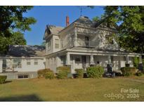 Two-story house with wrap-around porch and mature landscaping at 115 S Pearl St, Troy, NC 27371