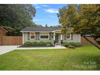 Gray brick ranch home with landscaped lawn and wooden fence at 5008 Unaka Ave, Charlotte, NC 28205