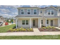 Two-story townhome with gray and white brick exterior, covered porch, and landscaping at 105 Ciara Pl # A, Mooresville, NC 28117