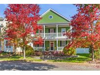 Two-story green house with wrap around porch, brick steps and landscaping at 14108 Tooley St, Huntersville, NC 28078