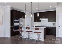 Modern kitchen with dark cabinetry, island, and stainless steel appliances at 5676 Clear Creek Ln, Charlotte, NC 28215