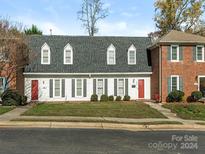 Brick and white townhouse exterior with a red door and well-manicured lawn at 8002 Regent Park Ln, Charlotte, NC 28210