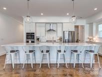 Modern kitchen with white cabinets, large island, and stainless steel appliances at 13702 Tranquil Day Dr, Matthews, NC 28105