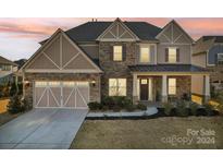 Two-story house with stone and shingle accents, three-car garage, and covered porch at 4027 Wiltshire Ln, Indian Land, SC 29707