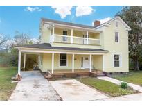 Two-story yellow house with front porch, driveway, and landscaping at 305 Elm St, Lancaster, SC 29720