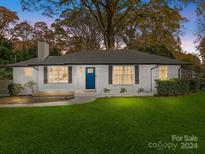 Charming ranch home with white brick exterior, landscaped lawn, and a blue front door at 201 Seneca Pl, Charlotte, NC 28210