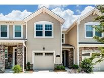 Tan two-story townhome with stone accents and a two-car garage at 14862 Tamarack Dr, Charlotte, NC 28278