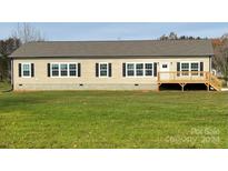 Beige single-story house with a wooden deck and a spacious lawn at 568 Drumstand Rd, Stony Point, NC 28678