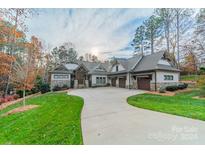 Brick house with stone accents, three-car garage, and landscaped lawn at 7978 Silver Jade Dr, Denver, NC 28037