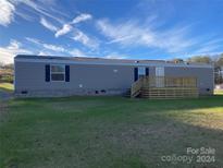 Single-wide manufactured home with a deck and grassy yard at 100 Debby Dr, Shelby, NC 28152