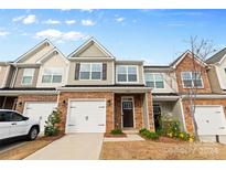 Two-story townhome with brick and siding exterior, two-car garage, and landscaped front yard at 3950 Rothwood Ln, Harrisburg, NC 28075