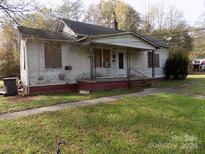 White frame house with boarded windows, needing repairs at 523 Hoyle St, Dallas, NC 28034