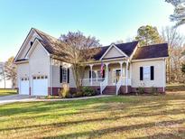 Beige house with a two-car garage, front porch, and landscaped lawn at 827 Hathcock Glen Dr, Oakboro, NC 28129