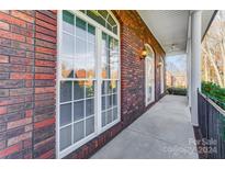 Brick front porch with entryway and wrought-iron railing at 8420 Locksley Dr, Harrisburg, NC 28075