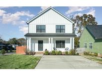 Two-story farmhouse style home with white siding, black windows, and a front porch at 305 Piedmont Ave, Mount Holly, NC 28120