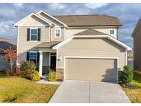 Two-story house with beige siding, a two-car garage, and landscaping at 5021 Markfield Ln, Monroe, NC 28110