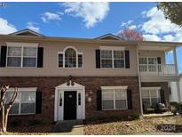 Two-story condo building with brick and siding, featuring a balcony and ample windows at 19744 Feriba Pl, Cornelius, NC 28031