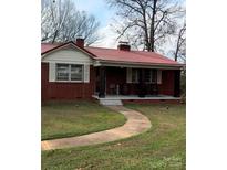 Brick ranch house with red metal roof, covered porch, and landscaped yard at 955 Goodnight Rd, Salisbury, NC 28147