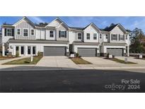 Four townhouses with gray and white exterior, two-car garages and landscaping at 2113 Bayou Trace Dr, Charlotte, NC 28262