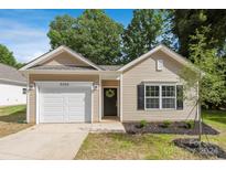 Tan house with white garage door and landscaping at 1504 E Cole St, Gastonia, NC 28054