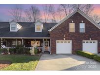 Brick front exterior of charming townhome with two-car garage and landscaped yard at 121 Quality Dr, Mount Holly, NC 28120