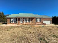 Brick ranch house with green metal roof, attached garage, and landscaped yard at 2945 Parks Lafferty Rd, Concord, NC 28025